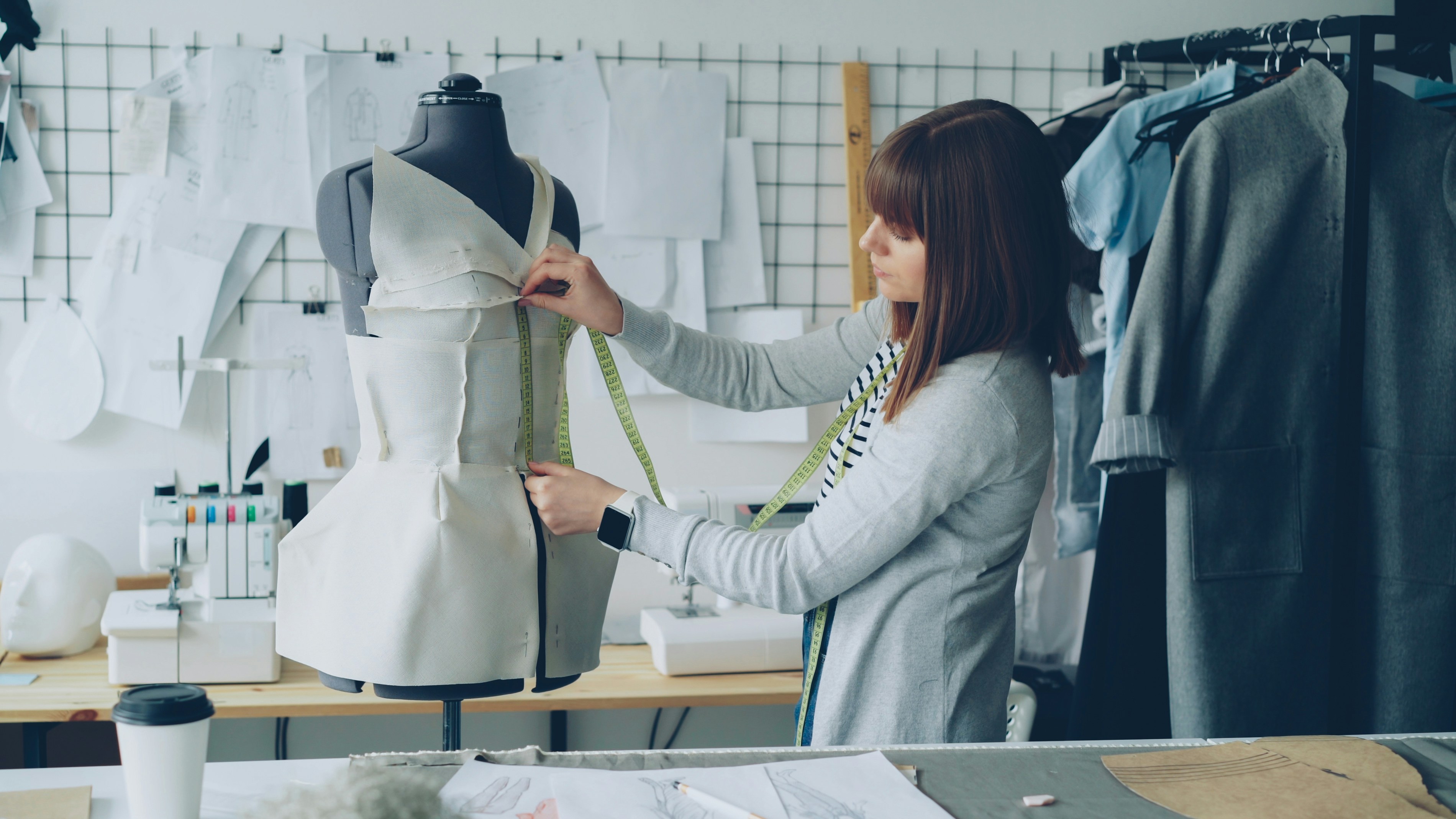 Fashion designer measuring a garment on a mannequin