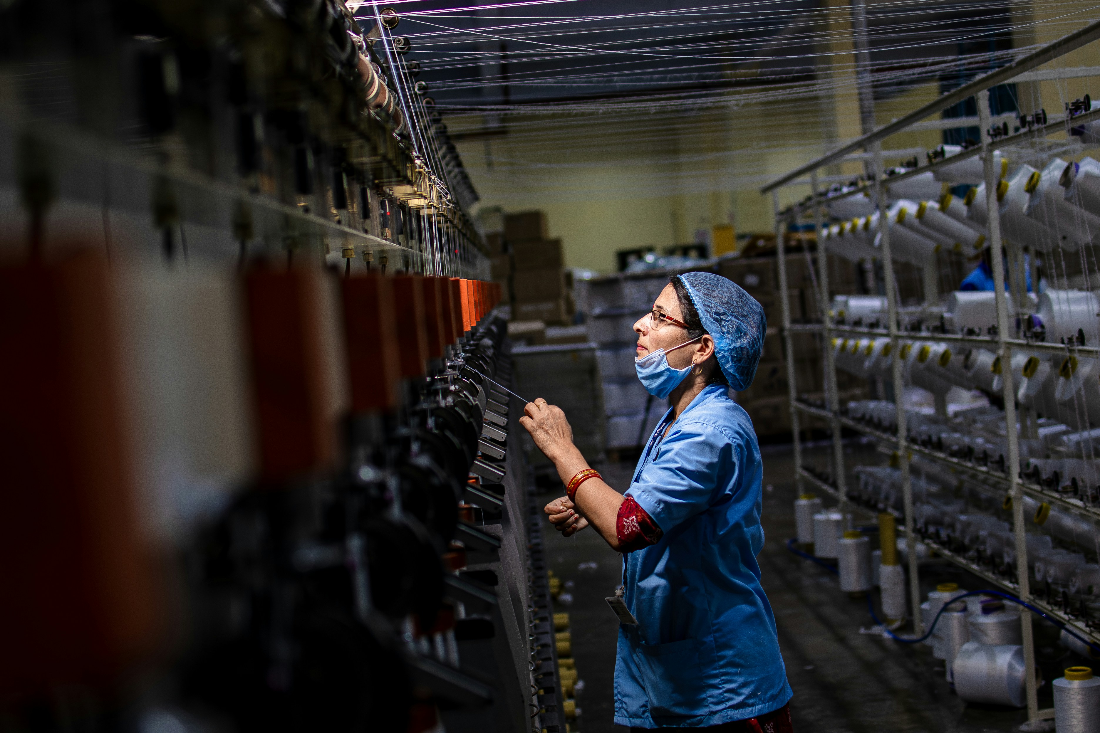 Factory worker checking textile machine threads